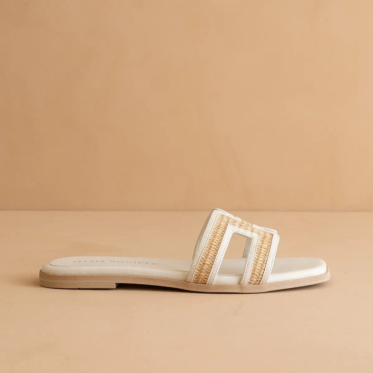 White sandal with gold buckle on a beige background