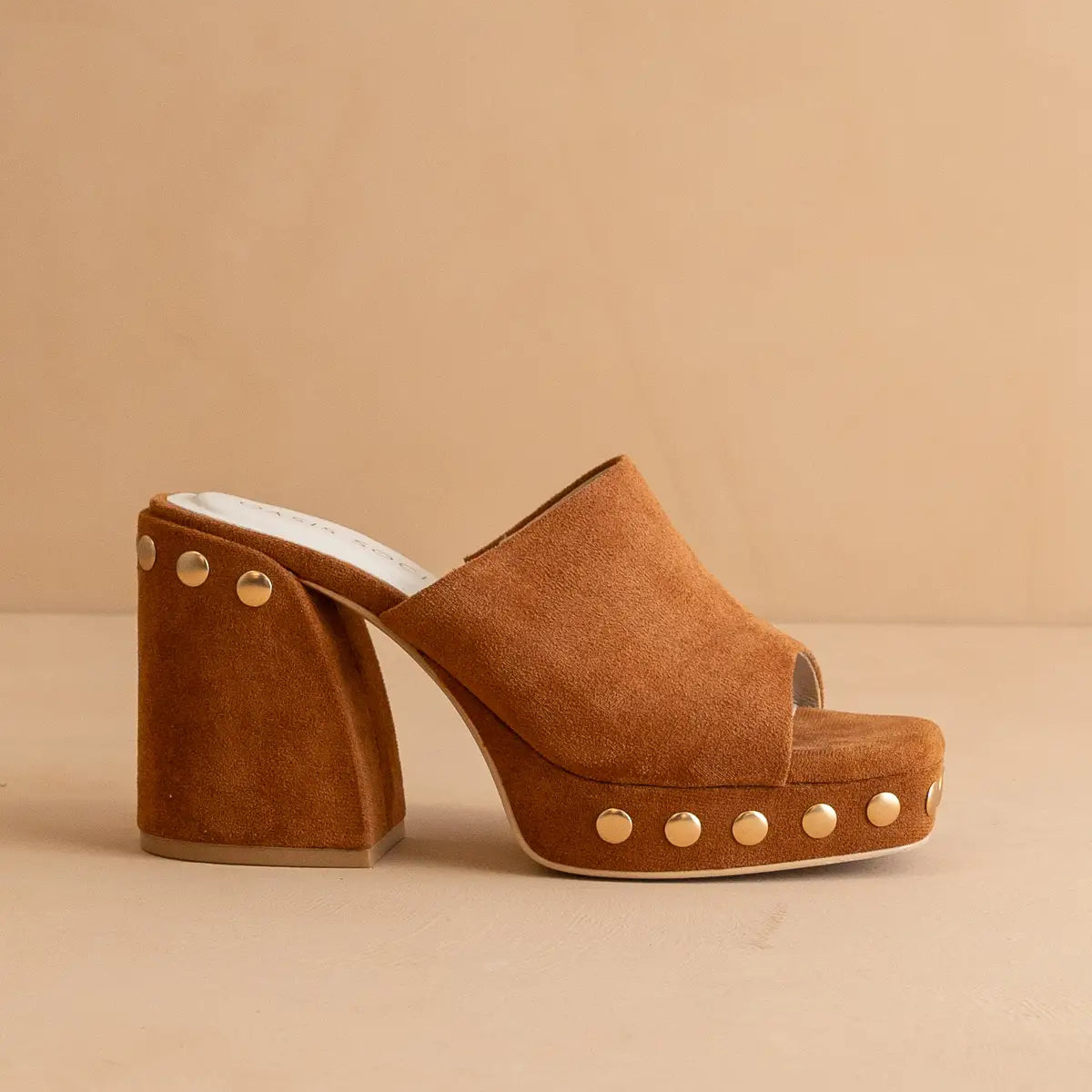 A caramel-colored suede platform heel with studs on the top and a square open toe.