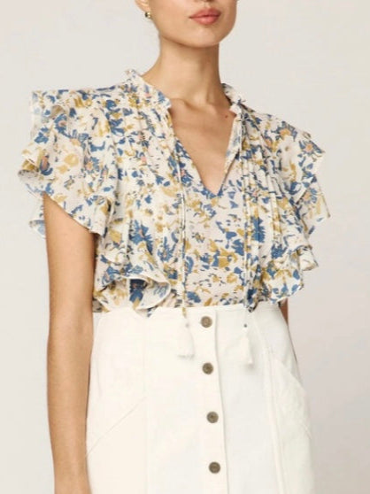 Woman wearing a floral top and white skirt with buttons on a plain background