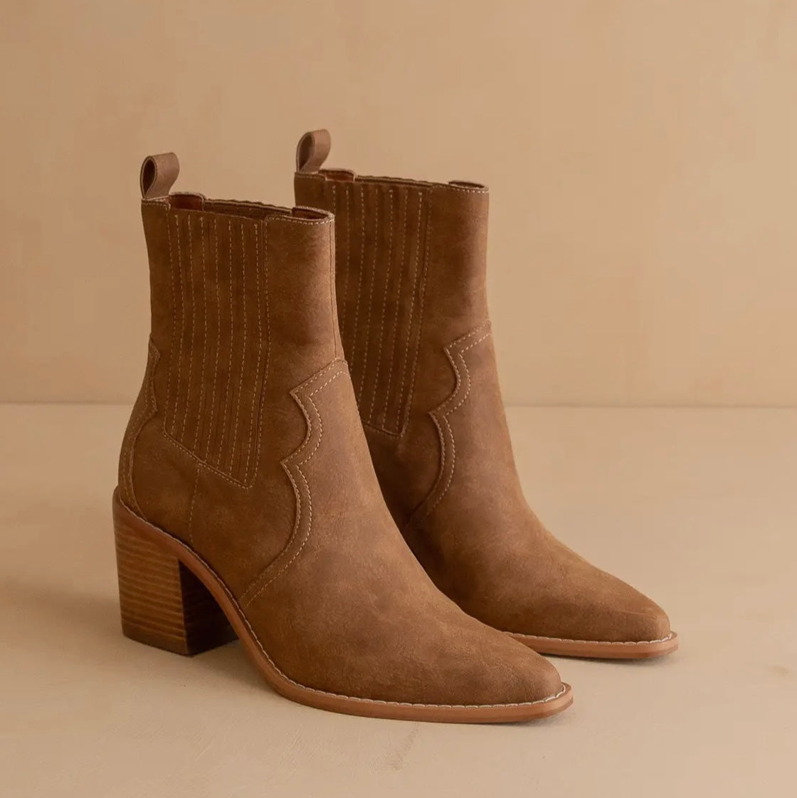 Pair of brown suede ankle boots on a beige background