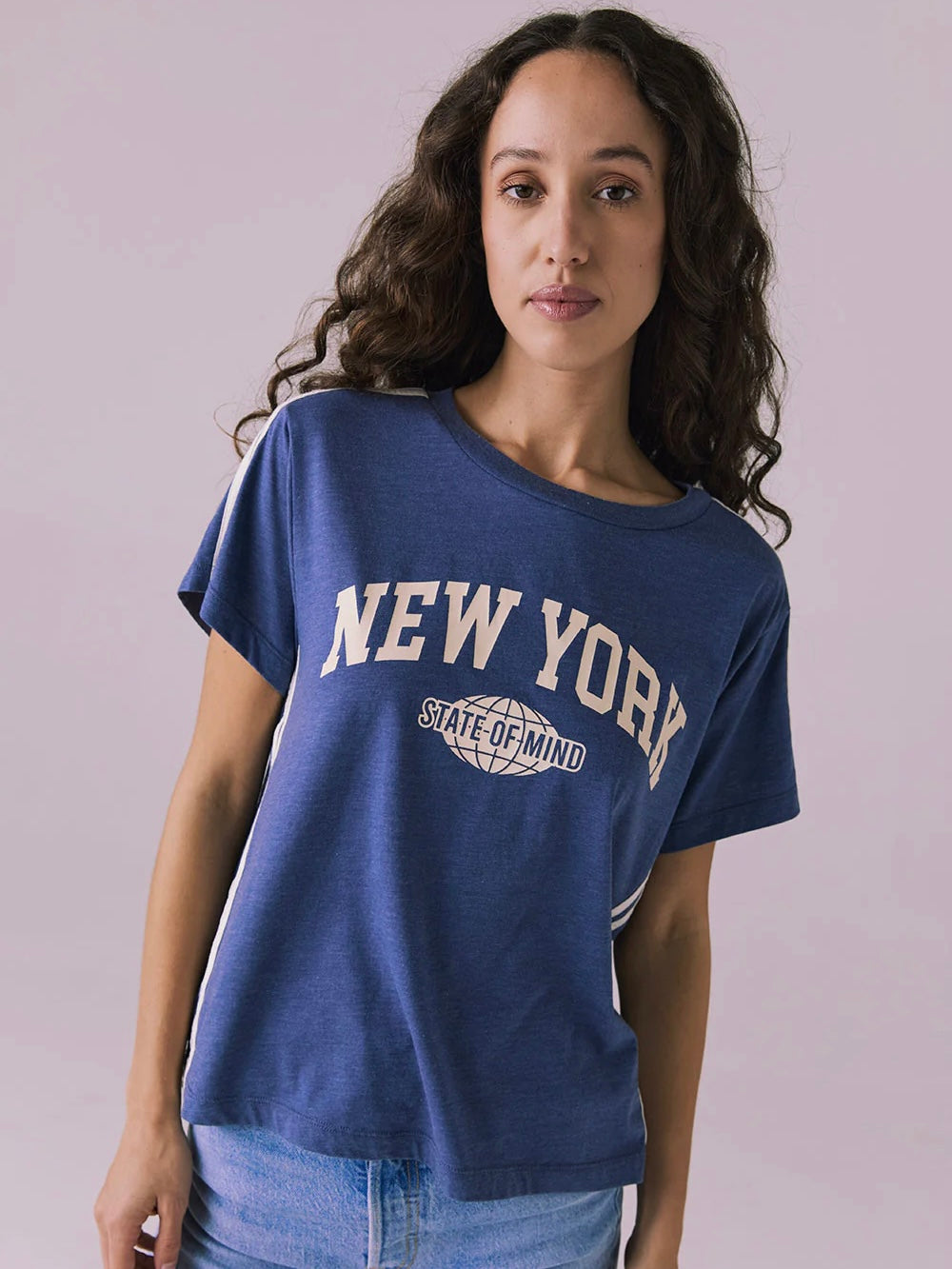 Woman wearing a blue 'New York State of Mind' t-shirt against a plain background