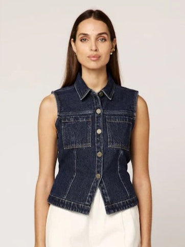 Woman wearing a denim vest over a white top on a plain background