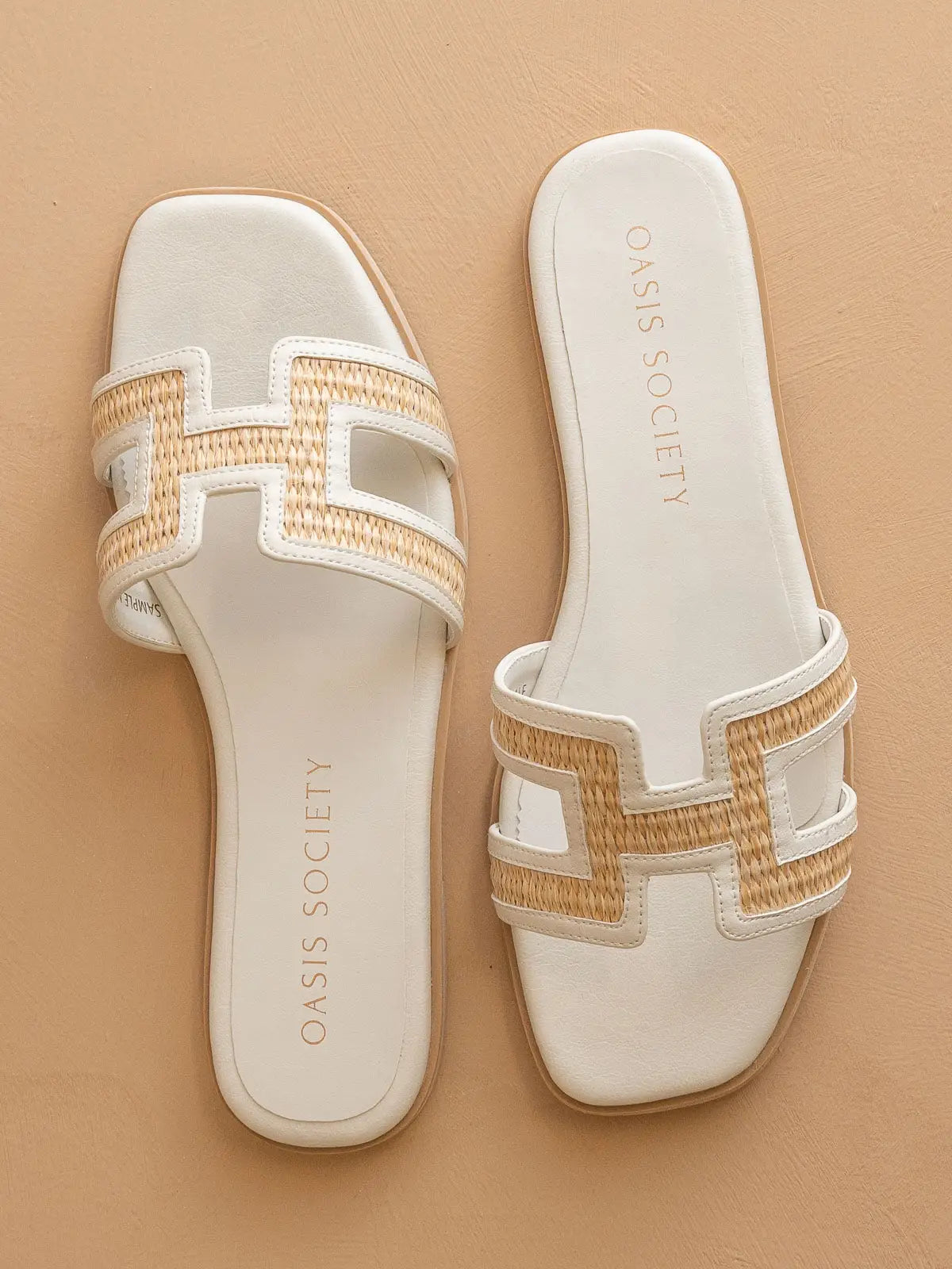 White sandals with gold accents on a beige background