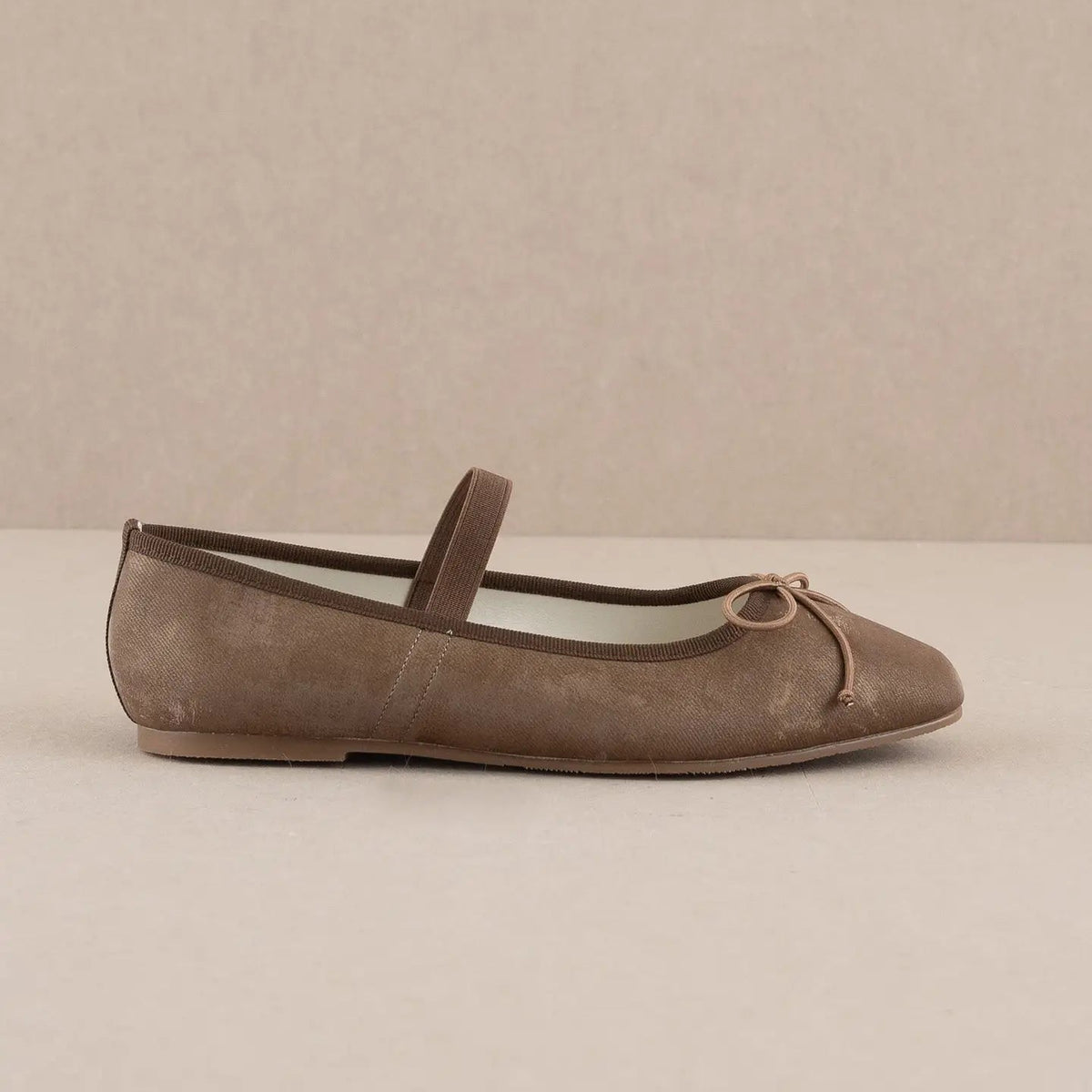 Brown ballerina shoe with a bow on a beige background