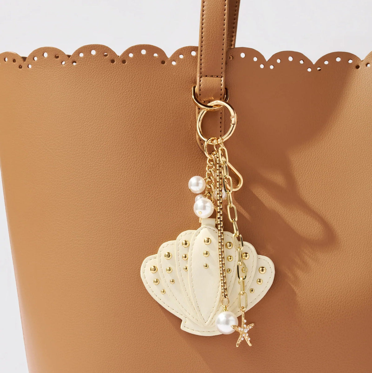 Shell-shaped keychain with pearls and a star on a brown bag.