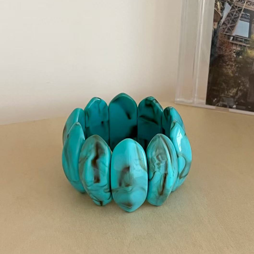 Turquoise bracelet on a beige surface with a blurred background