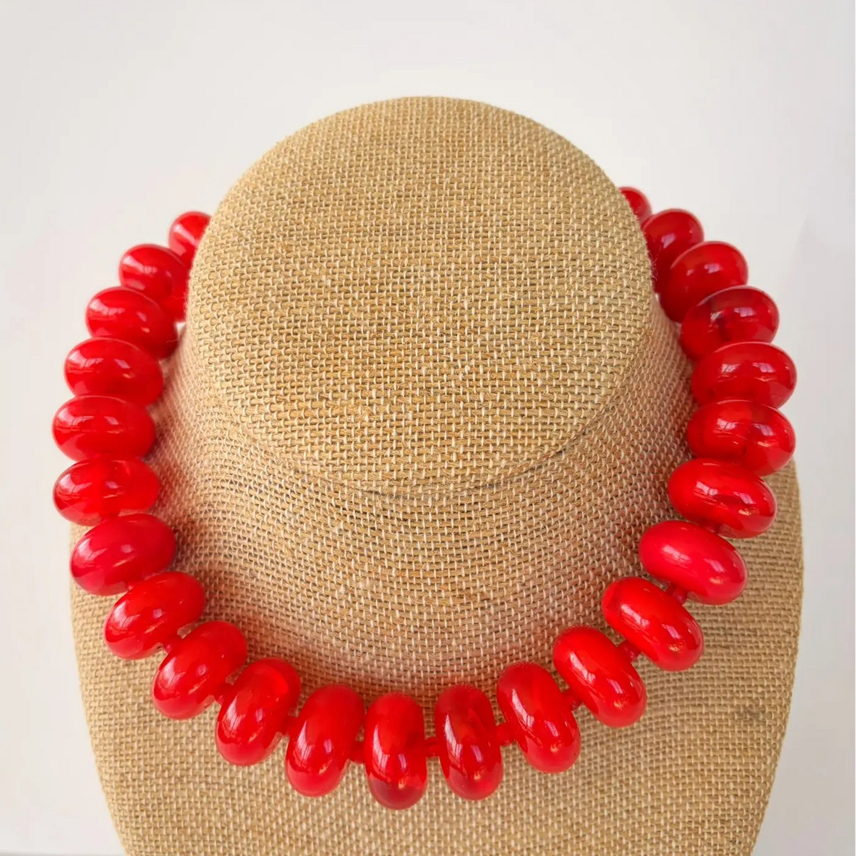 Red necklace on a mannequin head with a plain background
