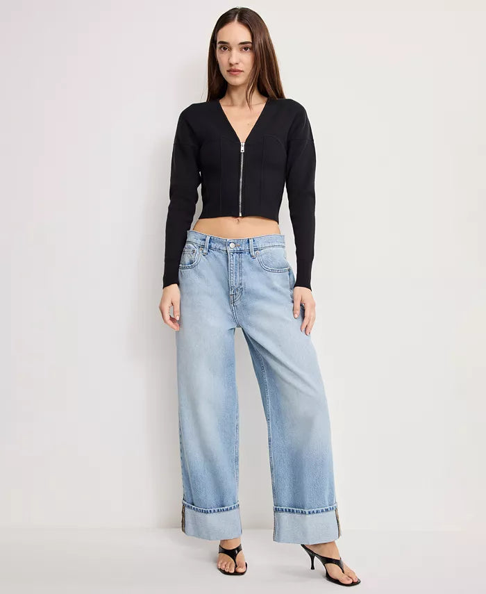 Woman wearing a black crop top and light blue jeans on a white background