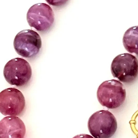 Three beaded strands of polished round gemstone beads in purple, teal, and pink, each with a gold clasp, arranged on a plain white background.