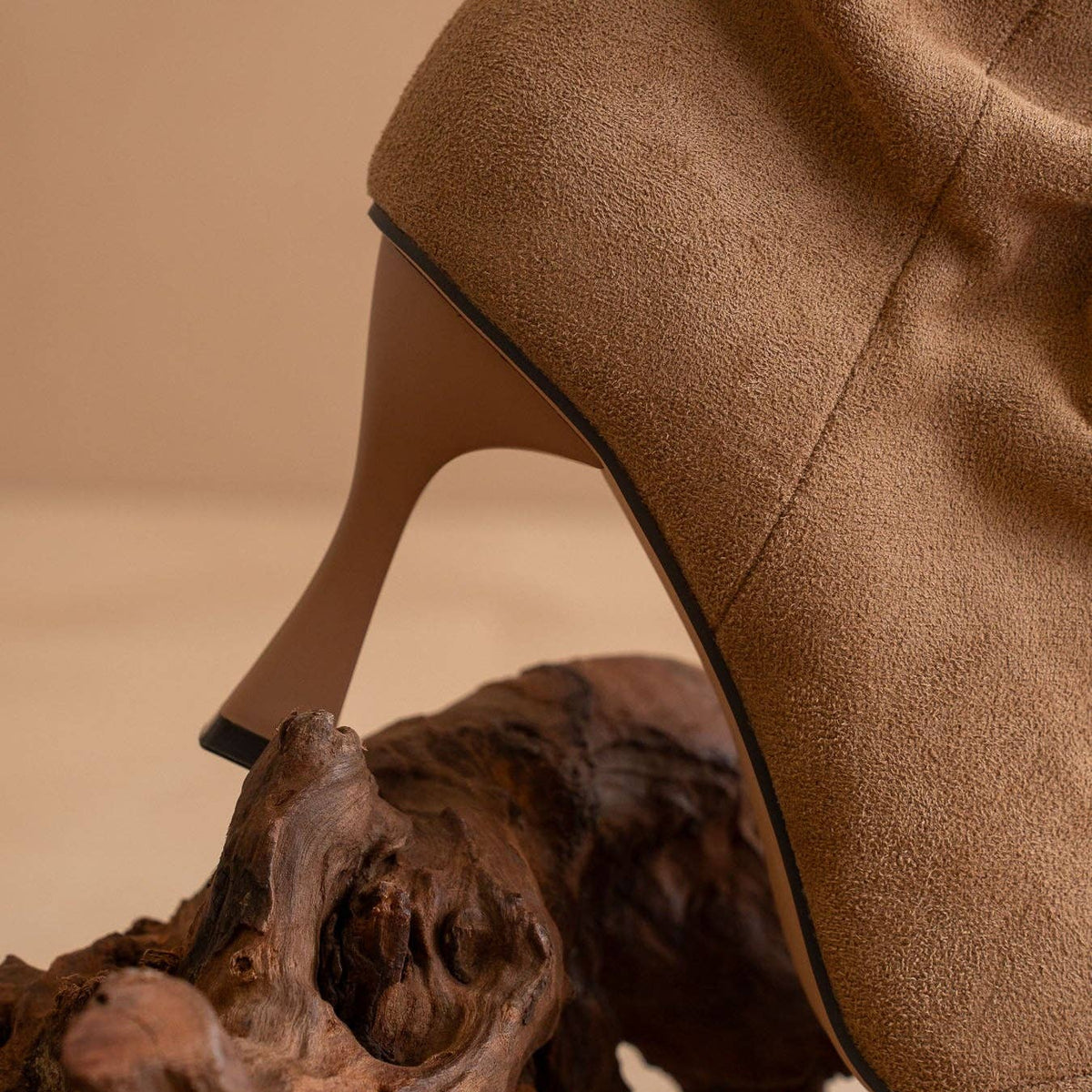 Brown high-heeled shoe on a textured surface with a neutral background