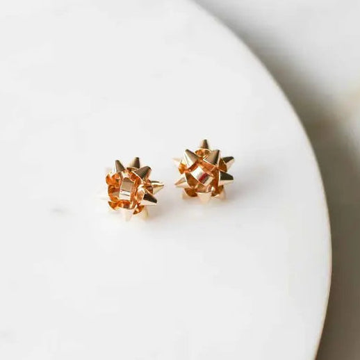 Gold star-shaped earrings on a white plate with a light background