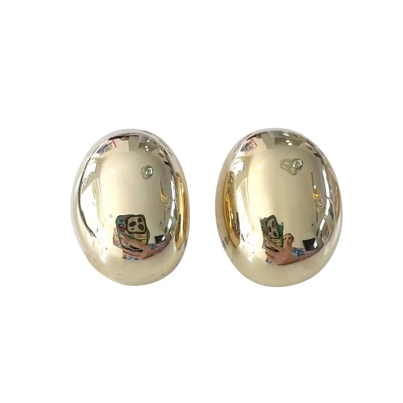 A pair of oval stud earrings with a polished, reflective gold finish, shown against a plain white background.