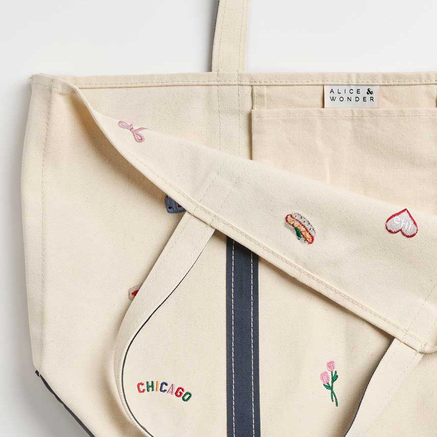 Beige tote bag with embroidered designs on a light gray background