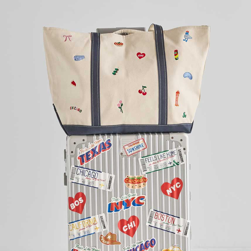 Luggage with travel-themed stickers and a matching cover on a light gray background