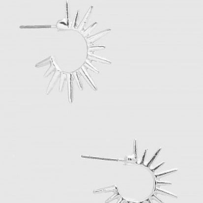 Silver sun-shaped earrings on a light gray background
