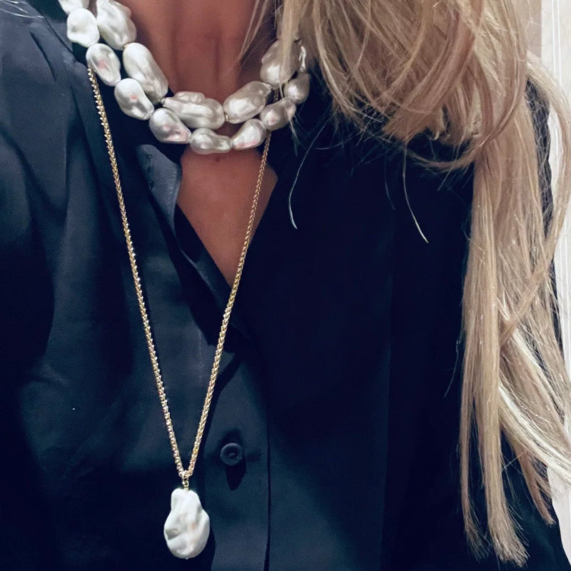 Person wearing a black outfit with pearl necklaces