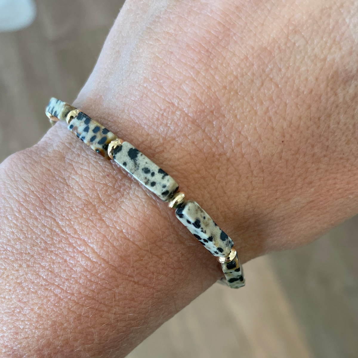 Bracelet with spotted pattern on wrist against a neutral background