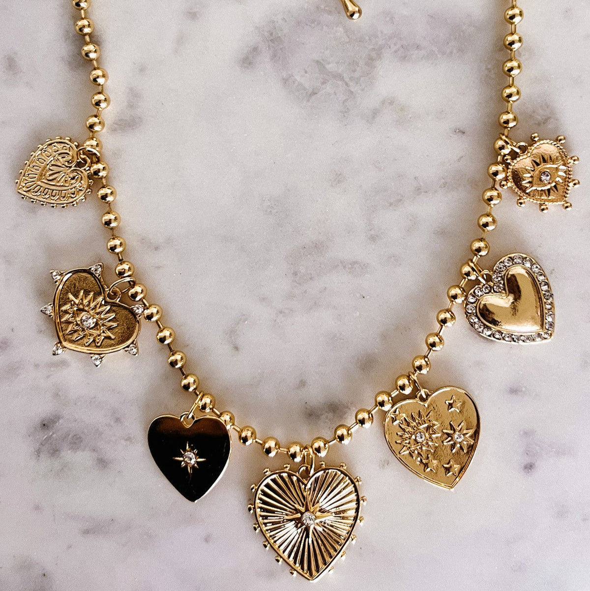 Gold necklace with heart-shaped charms on a marble surface