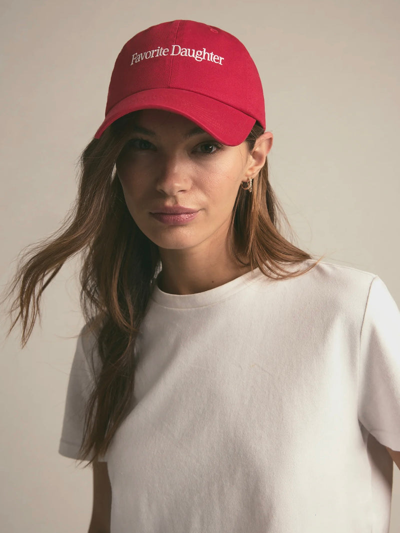 Woman wearing a red cap with 'Favorite Daughter' text on a plain background