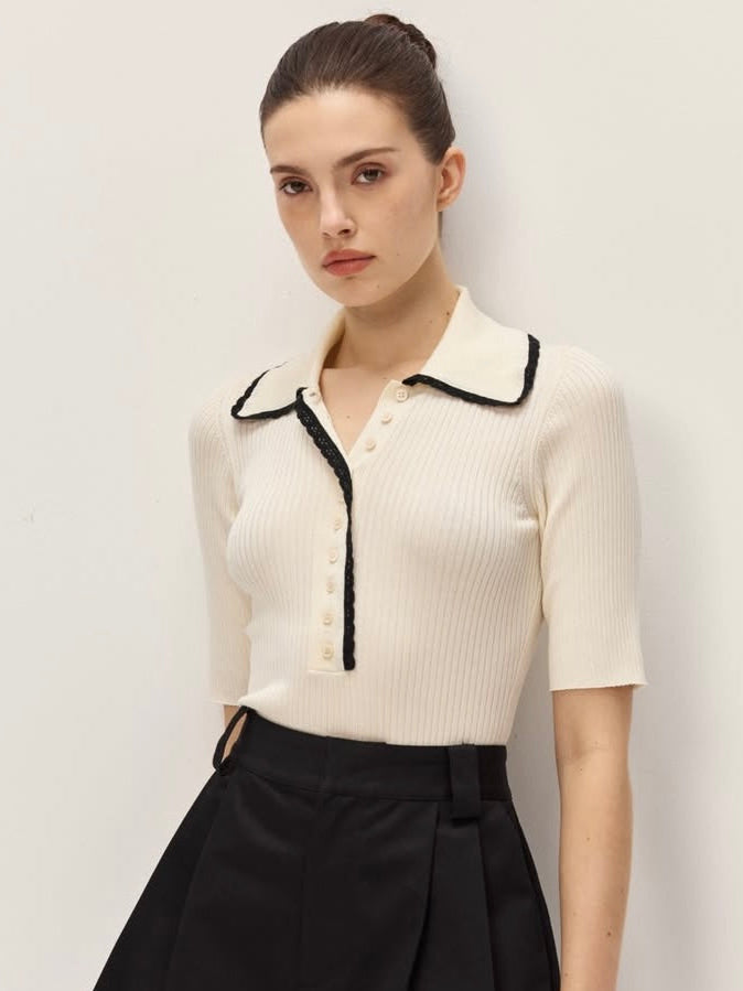 Woman wearing a white blouse with black trim and a black skirt against a plain background