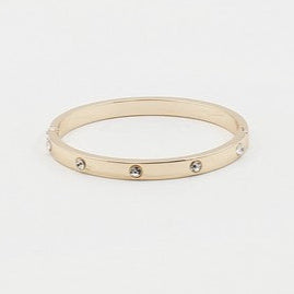 Gold bracelet with small stones on a light gray background