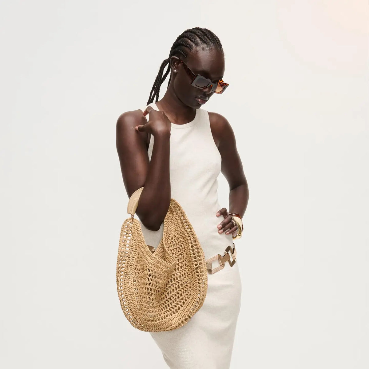 Woman holding a woven handbag against a plain background