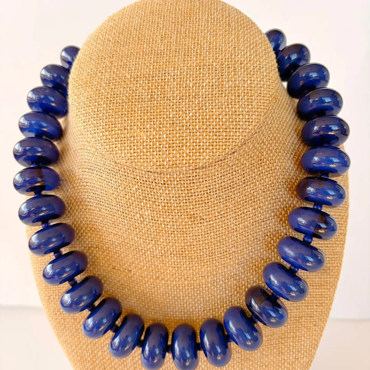 Blue beaded necklace on a tan mannequin head