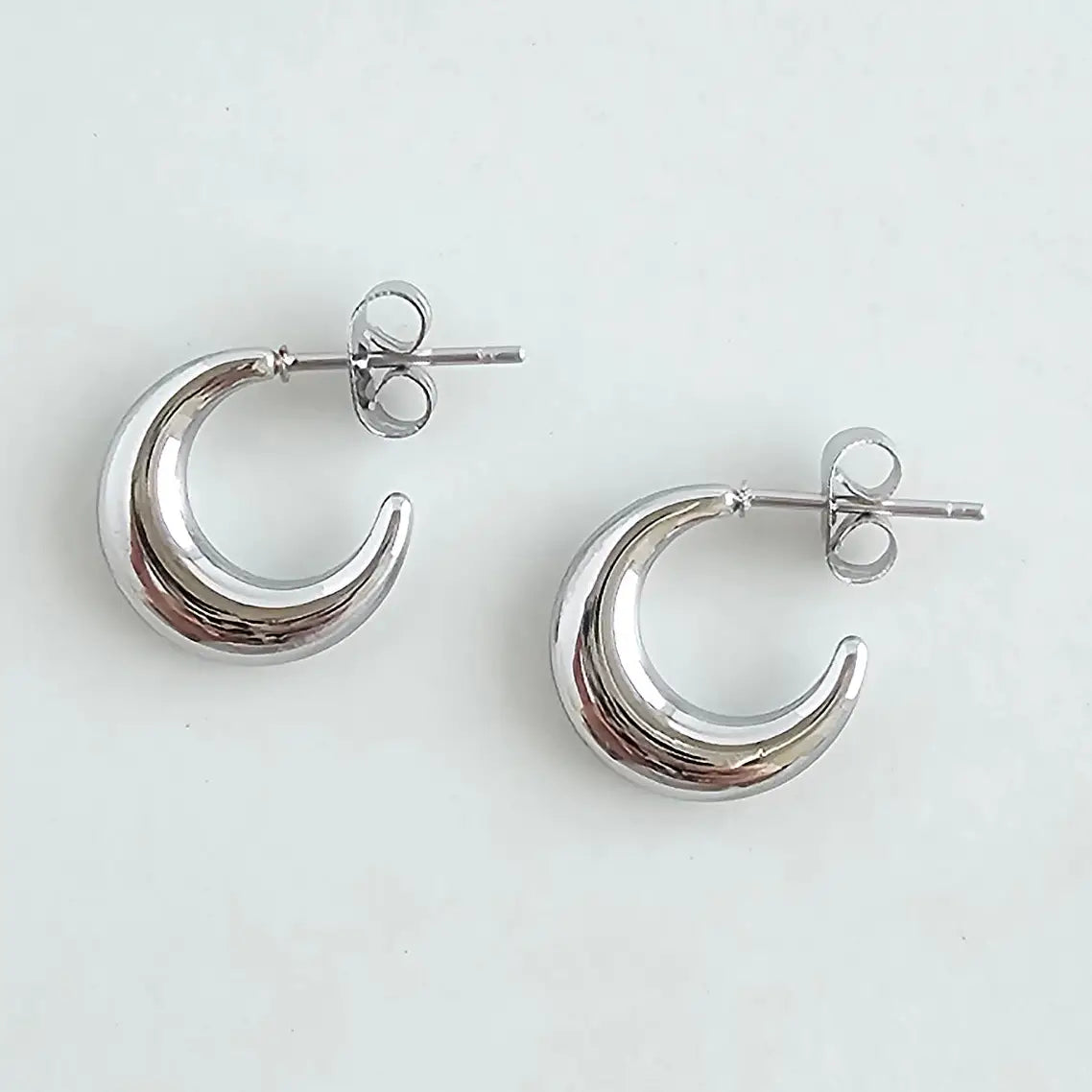 Silver crescent moon earrings on a light gray background