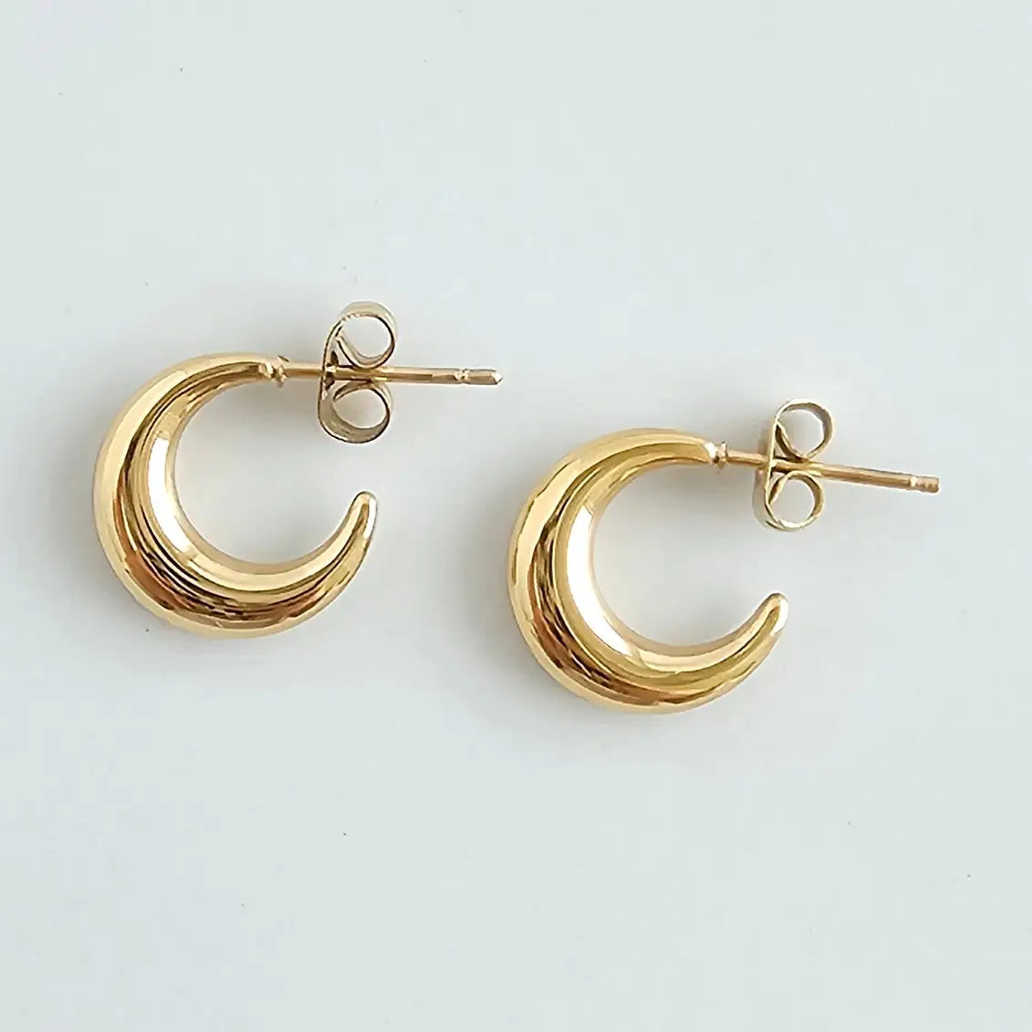 Gold crescent moon earrings on a light gray background