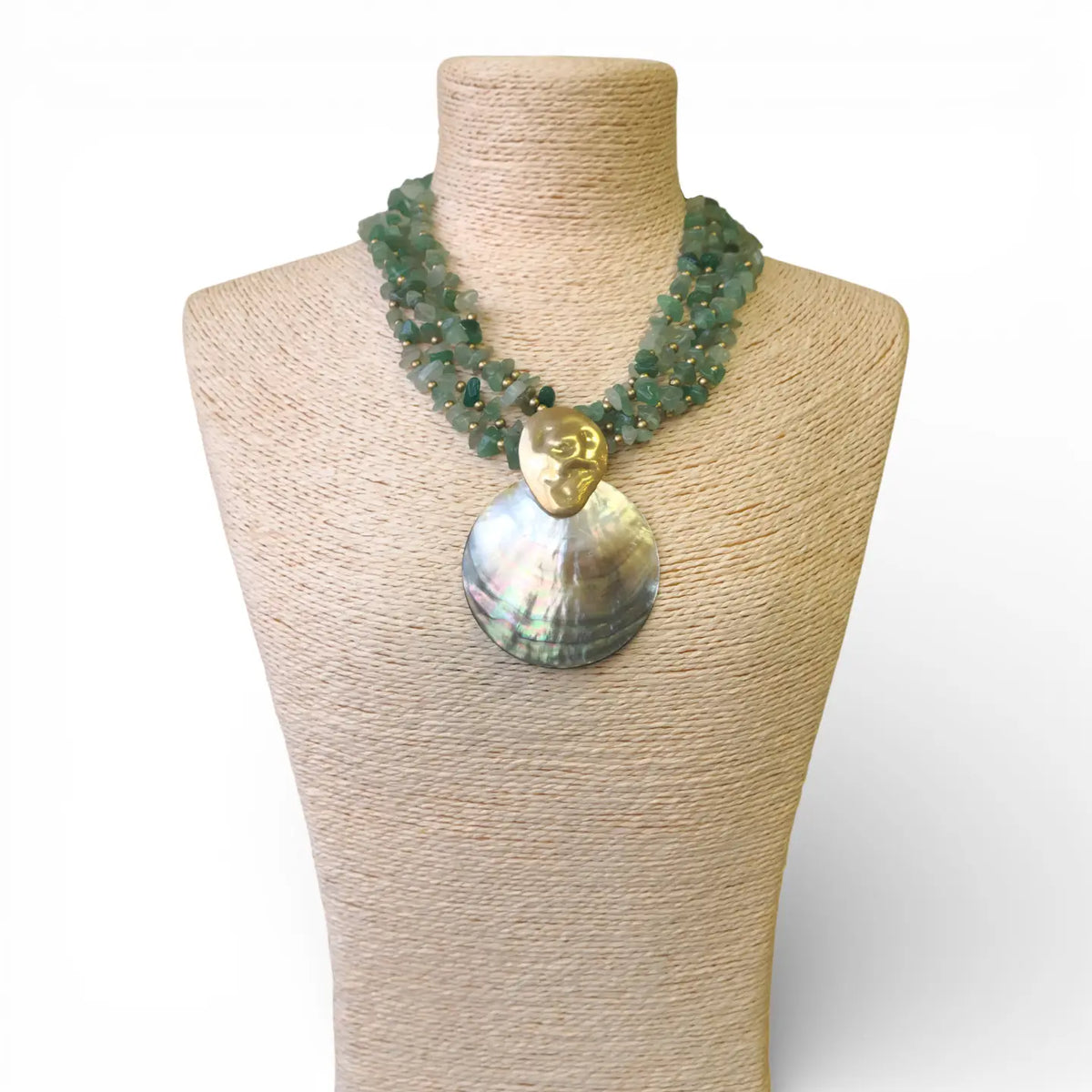 Necklace with a large shell pendant on a mannequin bust against a white background
