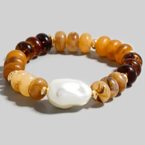 Multicolored beaded bracelet with a large white pearl on a gray background