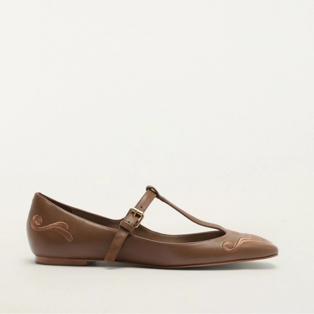 Brown flat shoe with a strap on a white background