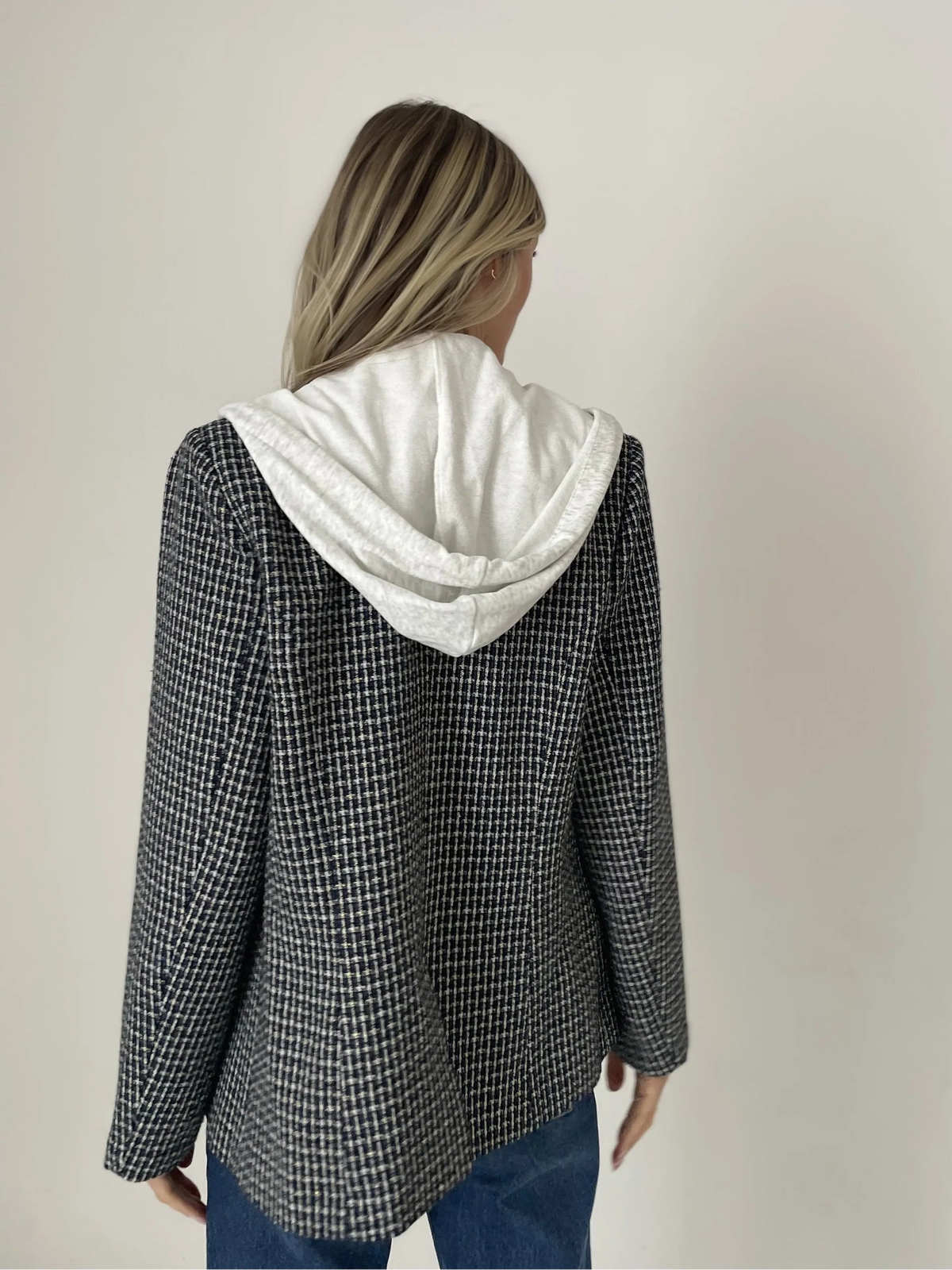 Person wearing a checkered jacket with a white hood against a plain background