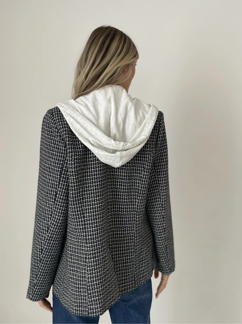 Person wearing a checkered jacket with a white hood against a plain background